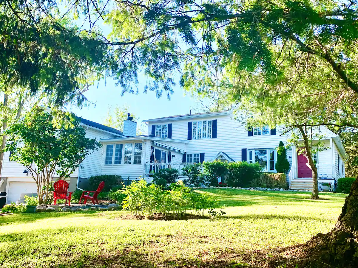 White farmhouse viewed through leafy trees