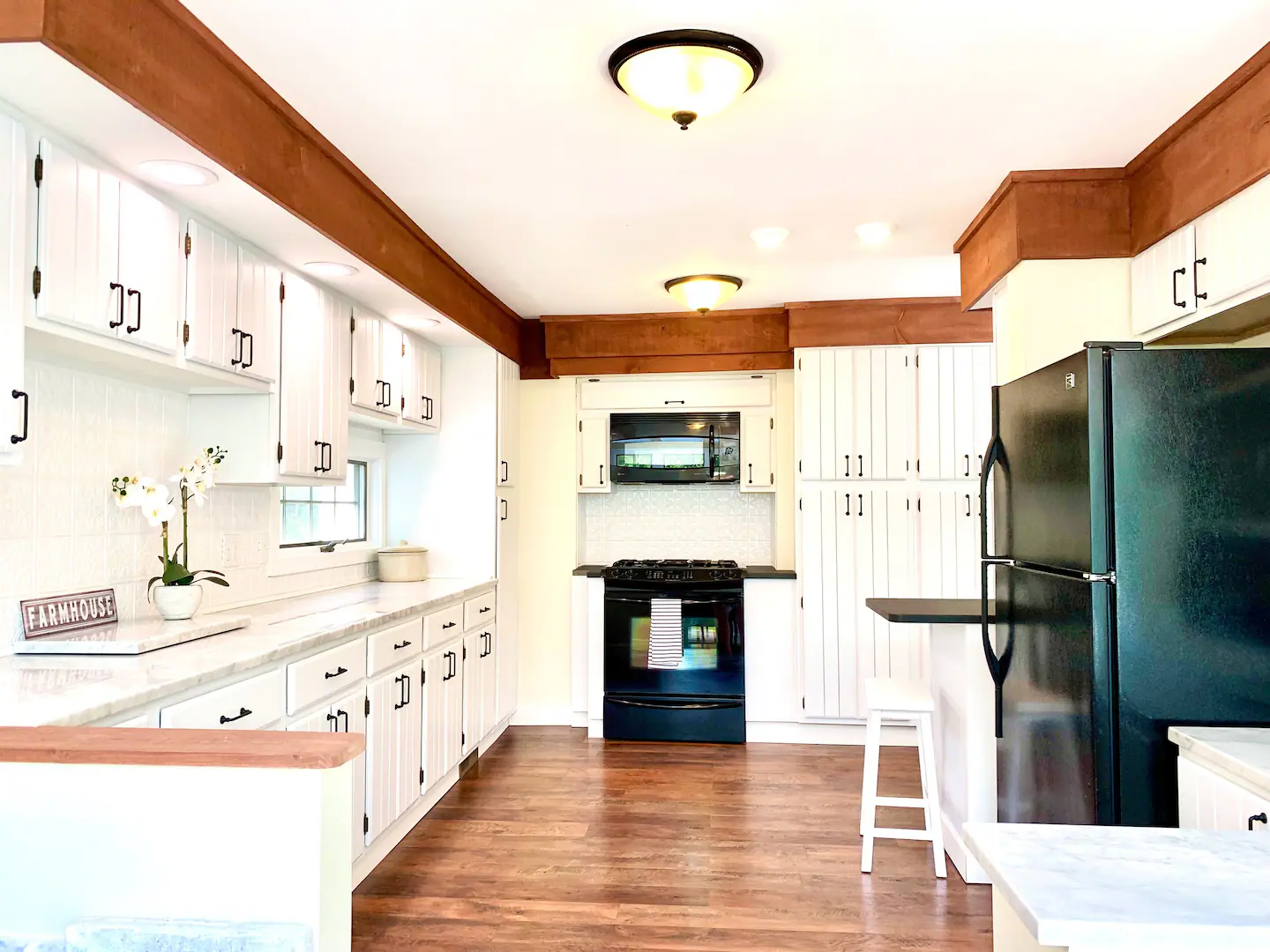 White kitchen with wood beams and black appliances